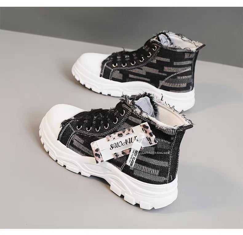 Black and white sneakers with a brand tag on a gray background