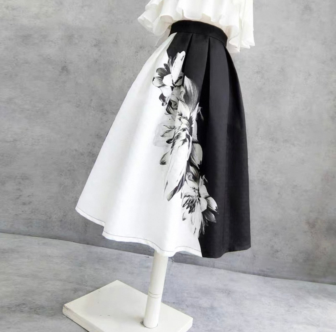 Skirt with black and white floral pattern on a mannequin against a gray background