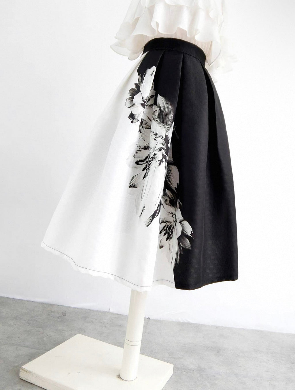 Mannequin wearing a black and white floral skirt with a plain background